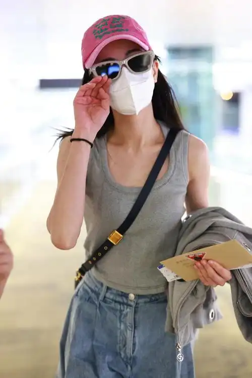 迪丽热巴机场照灰色背心77牛仔裤搭配棒球帽和墨镜