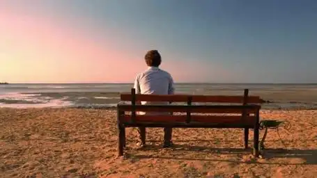 一个男人坐在椅子上看向远方的大海