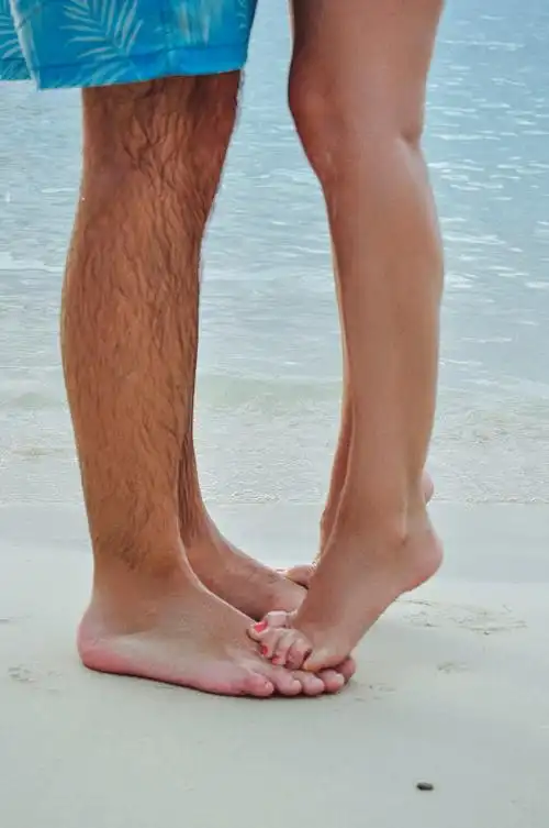 牙买加海滩上,一个赤脚女人踮着脚尖踩在一个男人脚上的特写图片下载