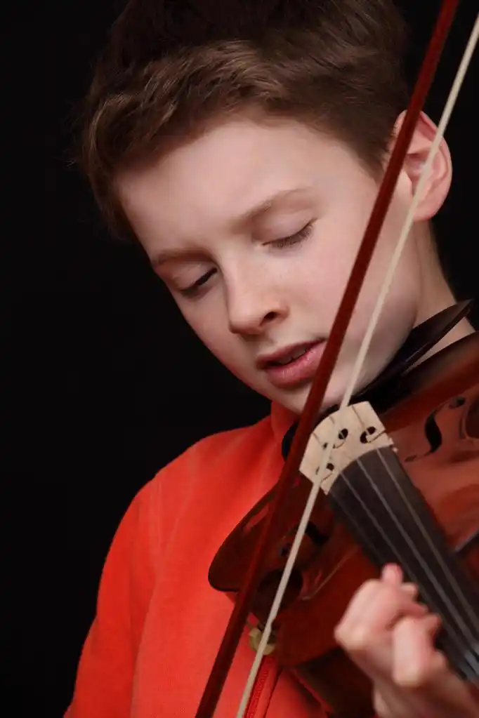 小提琴家,年轻的男孩在黑色背景上拉小提琴