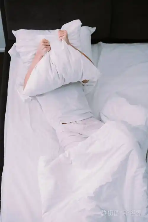 沮丧的女人躺在家里,用枕头遮住脸