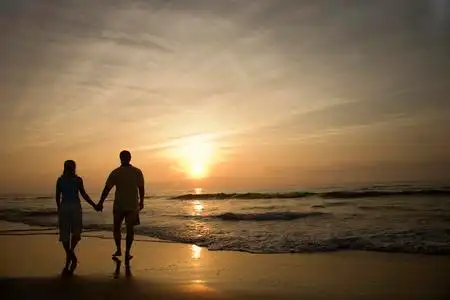 日落黄昏沙滩上散步的情侣照片