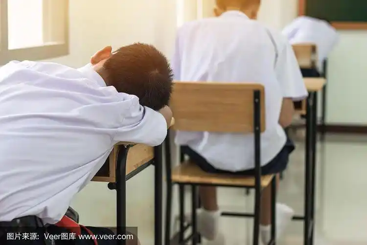 排在亚洲男孩后面的学生穿着校服睡觉在教室里考试,教育学校,上课坐在