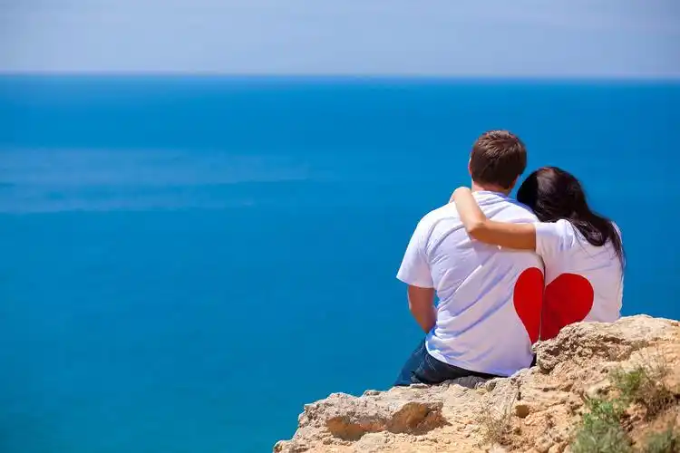 男女情侣相爱抱在一起看着蔚蓝的大海