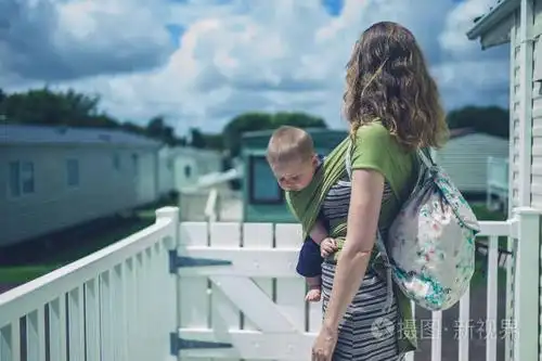 一个年轻的女人站在拖车公园里的一辆大篷车外面抱着她的孩子