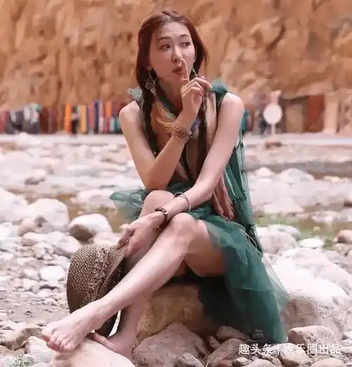 林志玲坐在石头上,用手做出了一个暗示大家小声一点的动作,这一张旧照
