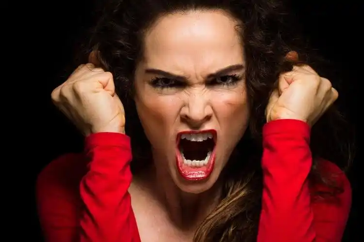 黑色背景中非常愤怒的女人气冲冲地握紧拳头