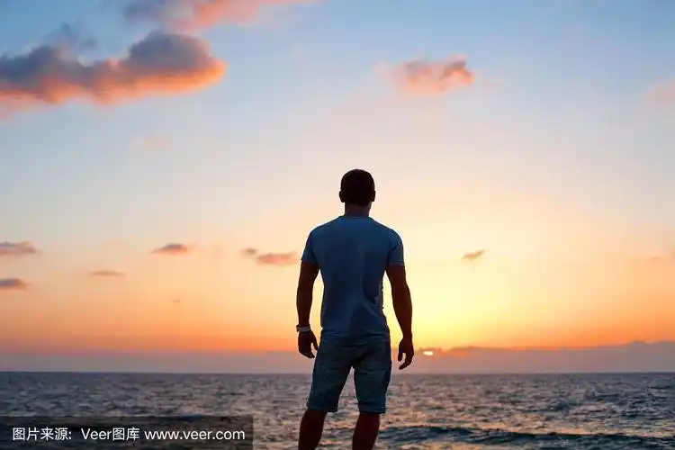 日落时,年轻人在海边剪影