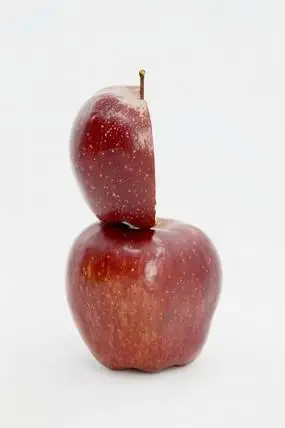 近拍一个苹果上放着切开的一半苹果图片