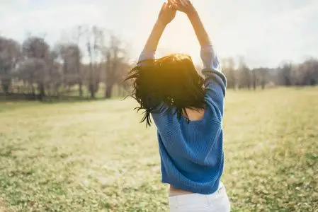 阳光透过厚厚的雾平静的大海和蓝天的背影欢呼的休闲女孩的背影可爱的