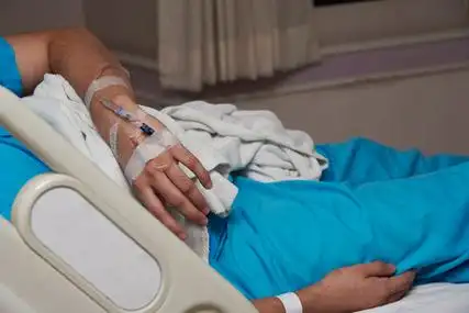 左手股票病人在病床上躺在床上, 左手输液, 在医院入院时照片