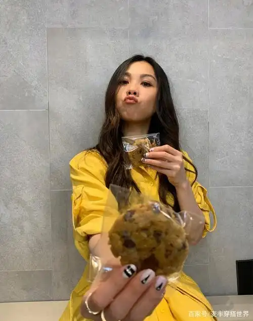 撅起嘴巴的蔡健雅长发飘飘,手拿两个点心做出搞怪表情,鹅黄色的长裙