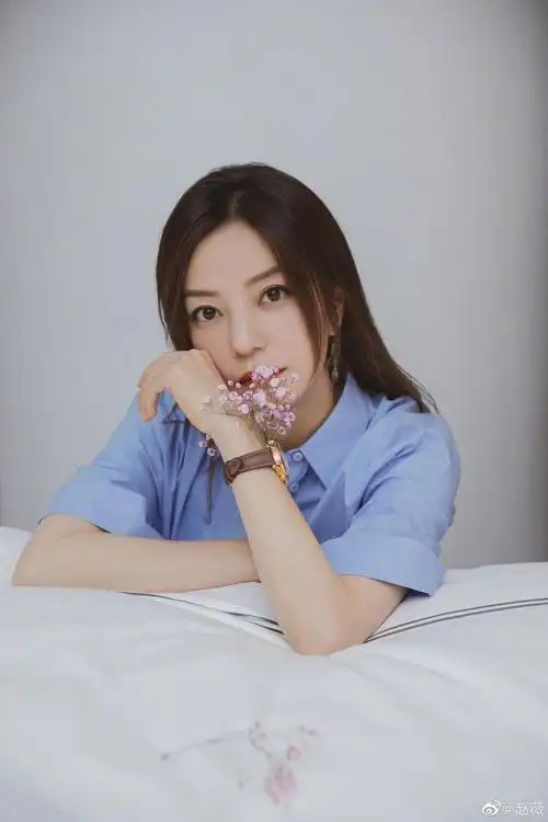 "晒出的照片中,赵薇一头直发,身穿蓝色短袖衬衣,手上戴着粉色满天星的