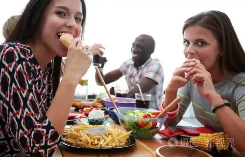 一群人在一起时坐在木桌吃饭照片-正版商用图片0w6qqf-摄图新视界