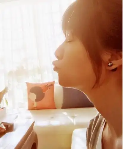 照片中的她似乎是在模仿自己的沙发抱枕,闭着眼睛嘟嘟嘴,显得十分甜美