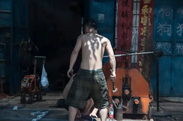 酷暑街头,一焊工师傅光着光膀子干活.