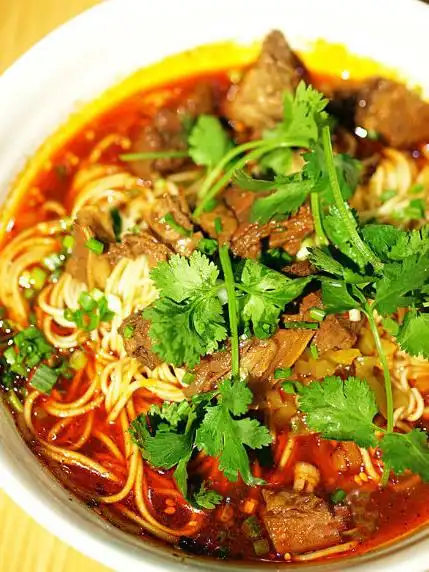 红烧牛肉面,酱红的汤底飘着红艳艳的油花,浓重的麻辣味"肆无忌惮地