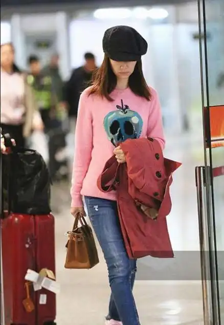 林心如穿粉色毛衣现身机场低头疾走手捂脸打哈欠显疲倦