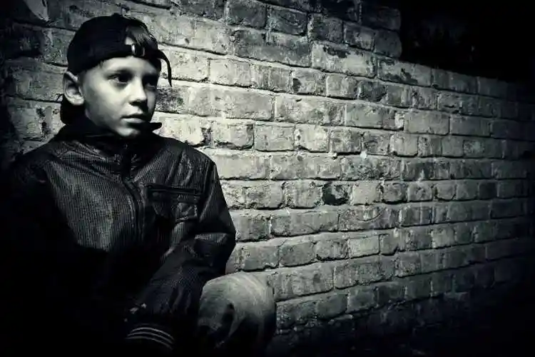 灰色青砖墙面前的小少年