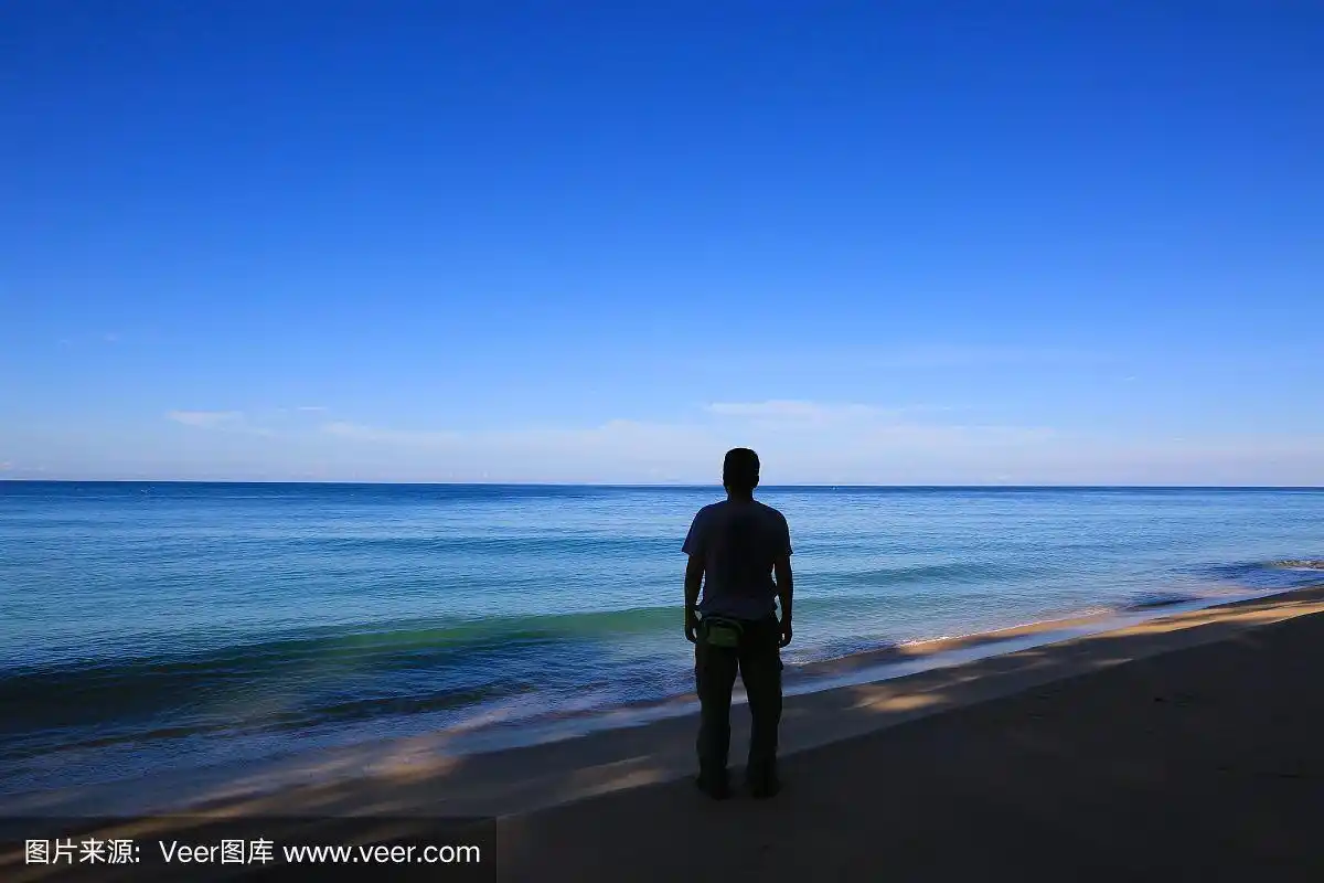 男人站在海滩上看大海和天空