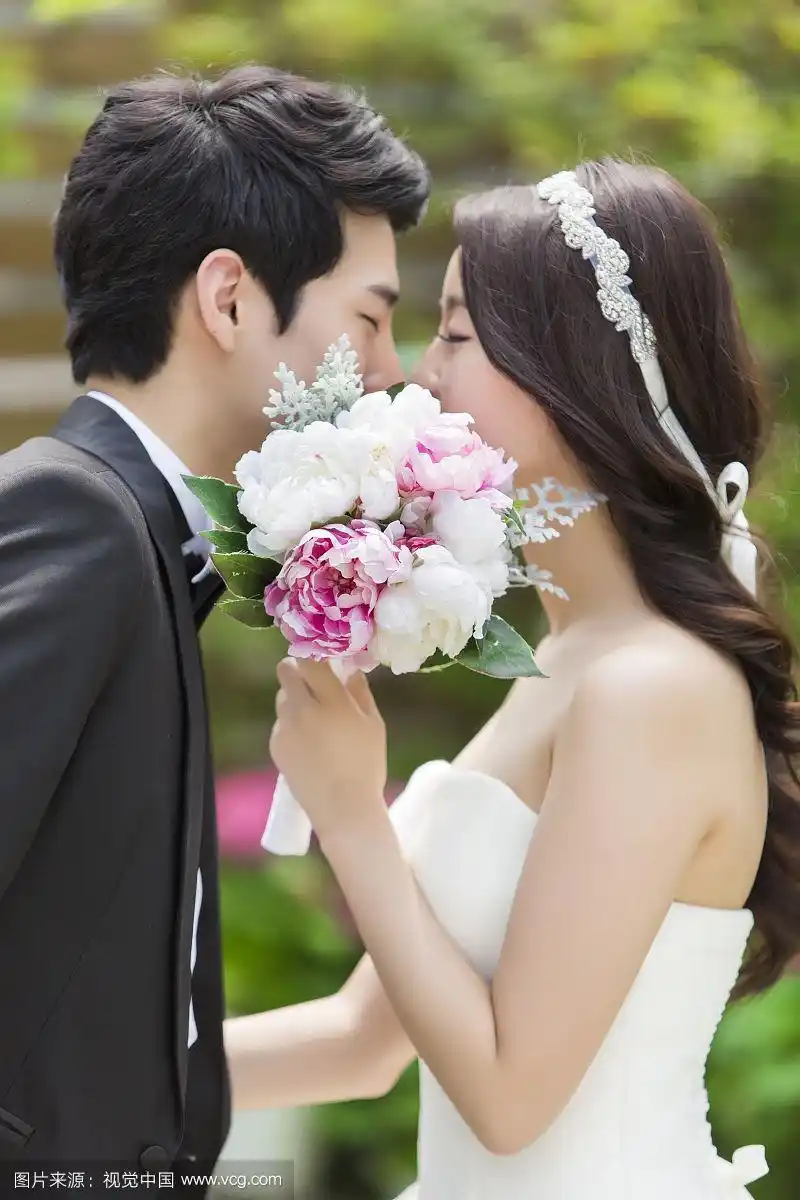 照片的夫妇与燕尾服和婚纱亲吻覆盖鲜花花束