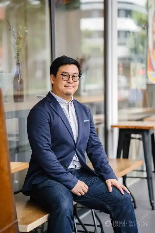 中年中国亚裔男子的肖像牛津衬衫夹克和牛仔裤的纽扣他戴着眼镜看上去