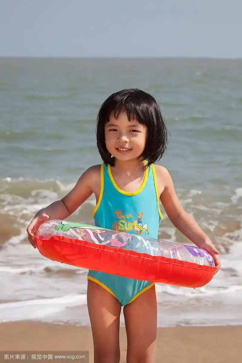 小女孩拿着游泳圈在海边玩耍