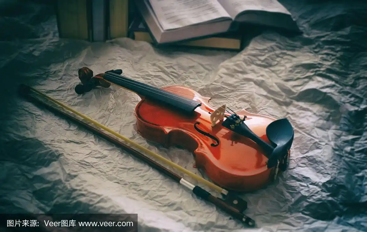 抽象的艺术设计背景古典小提琴和弓放在前面模糊的书堆叠,在背景上