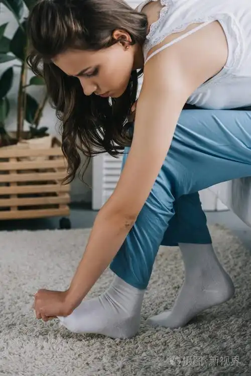 穿着睡衣的年轻女子坐在床上忍受脚痛