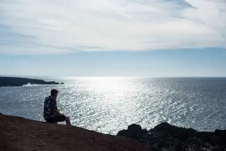 特兰戈一个人坐在石头上看着大海. 著名的埃尔戈沃·兰扎罗特海滩.