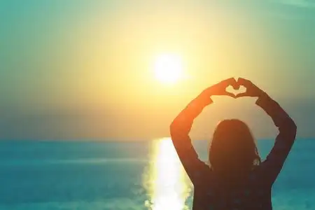 在海滩上用手做心脏形状的女孩照片