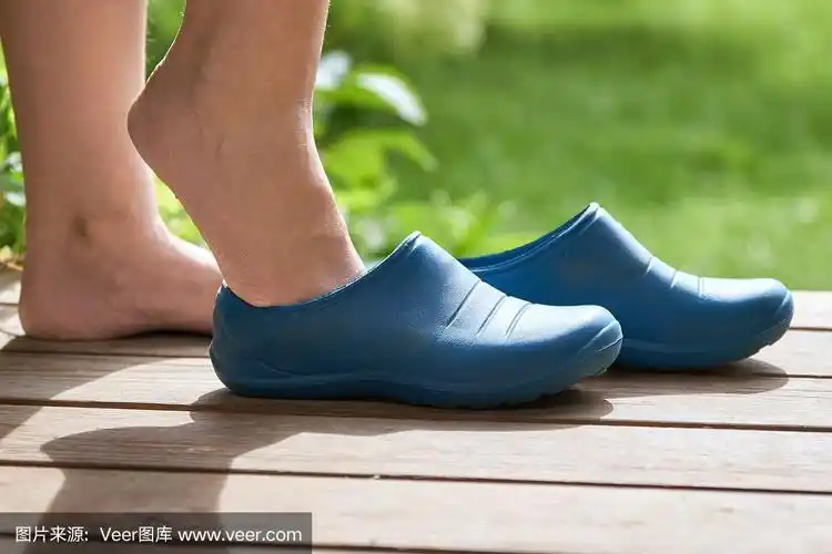 光着脚的女孩穿着胶靴站在一所乡村房子的门廊上