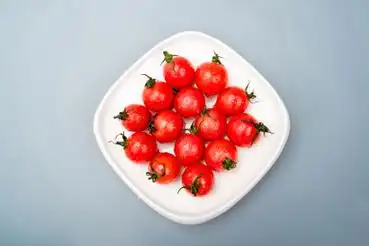 黑背景下摆放在白盘子里的小番茄