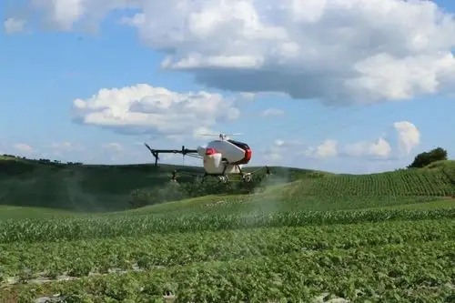 沈阳无距科技有限公司的x50农业植保无人直升机在悬停喷洒农药.