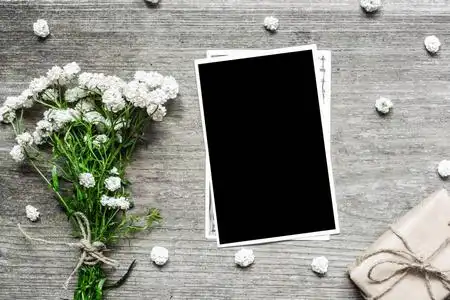 空白相片框架用白色花花束和礼物箱子放您的图片照片