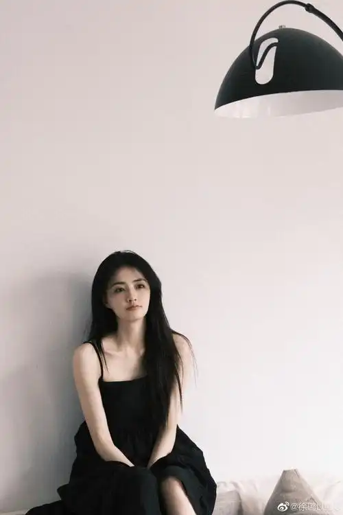 徐璐在个人社交平台晒出一组黑色连衣裙造型随拍,她披散长发在沙发上