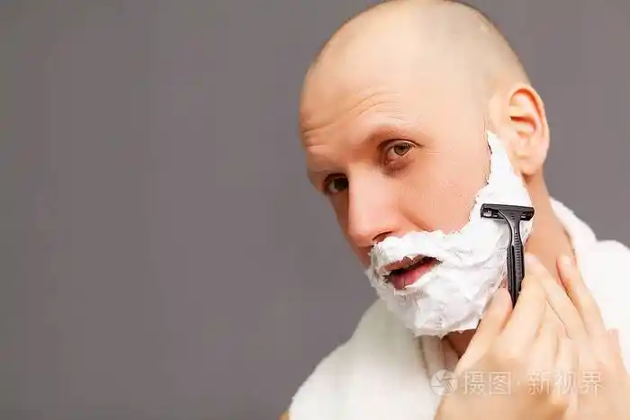 浴室里的男人用剃须刀刮胡子