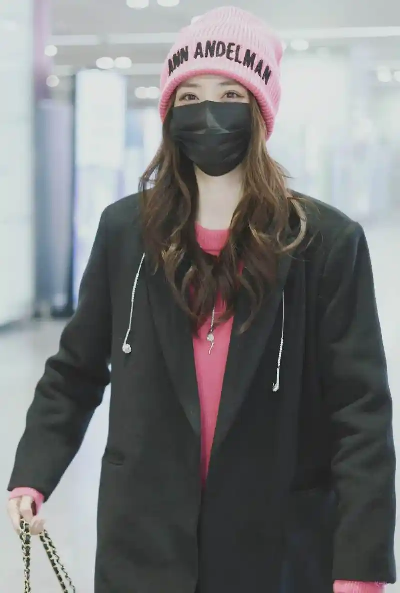 徐璐211210机场私服,黑色长外套搭配粉色毛衣和黑色皮裤,头戴粉色针织