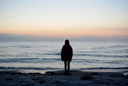 孤独的年轻女孩看着大海照片