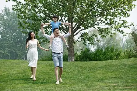 20多岁成年人25岁到29岁一家三口在草地上玩耍图片素材