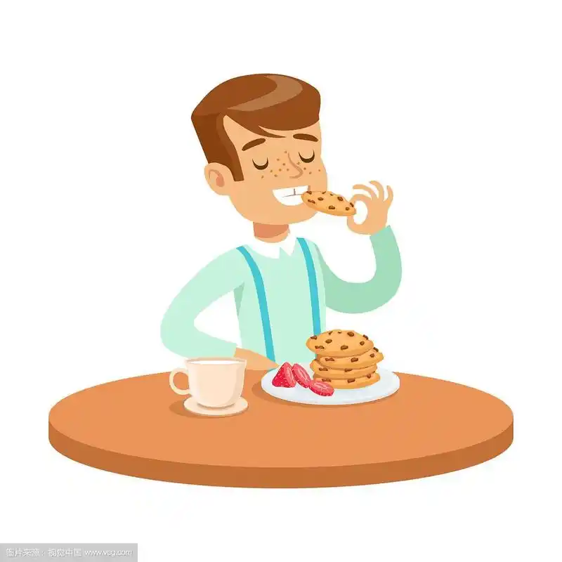 快乐的男孩坐在桌子边吃饼干