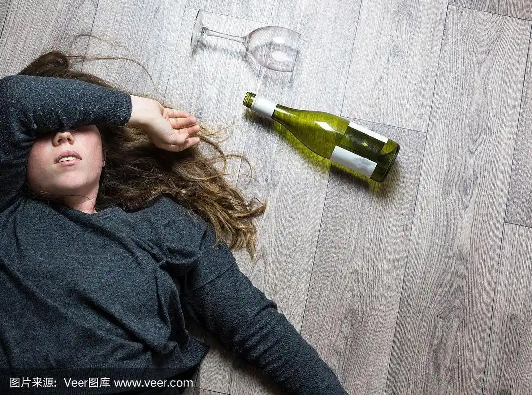 醉酒的酗酒少女躺在地板上感觉不舒服,喝了红酒,空杯子和酒瓶