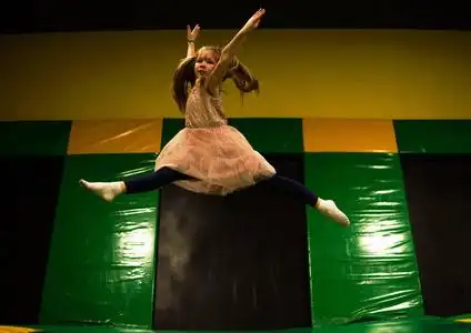 小女孩跳上蹦床, 在孩子们的游戏室里做绳子分开照片