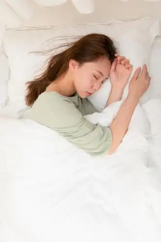 年轻女性躺在床上枕着枕头侧身睡觉俯拍