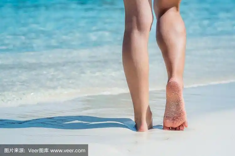 女性的脚走在沙滩上