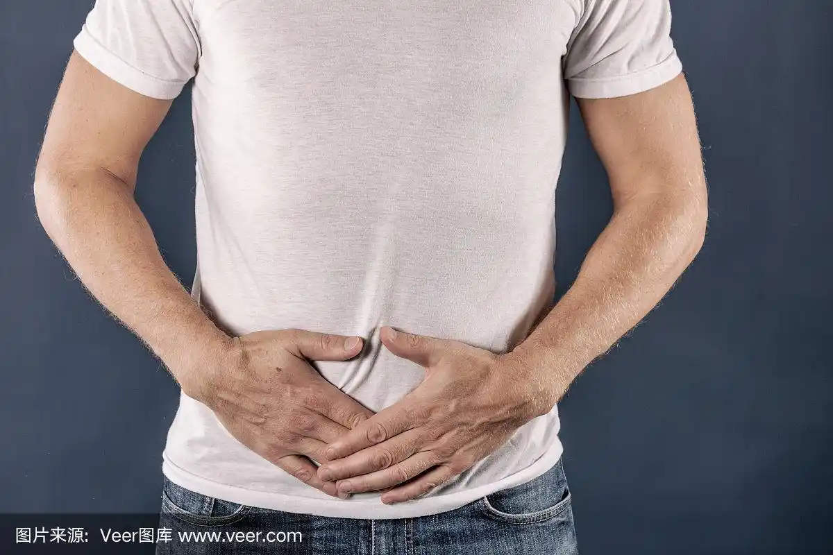 男人痛得捂着肚子.身穿白色t恤的男士在粉色背景下感到胃痛.