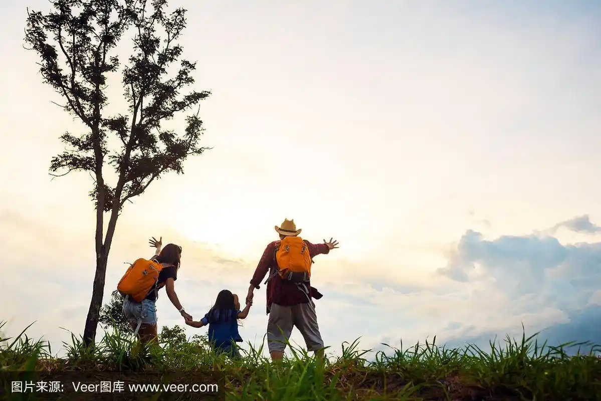 幸福的三口之家,母亲,父亲和孩子面前的夕阳天空.