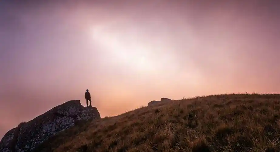 一个背着背包站在山顶上的男人的.
