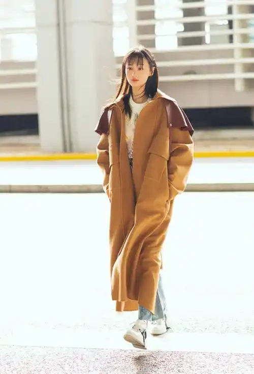 郑爽今日机场穿搭,选择焦糖棕长款大衣下搭白色运动鞋.