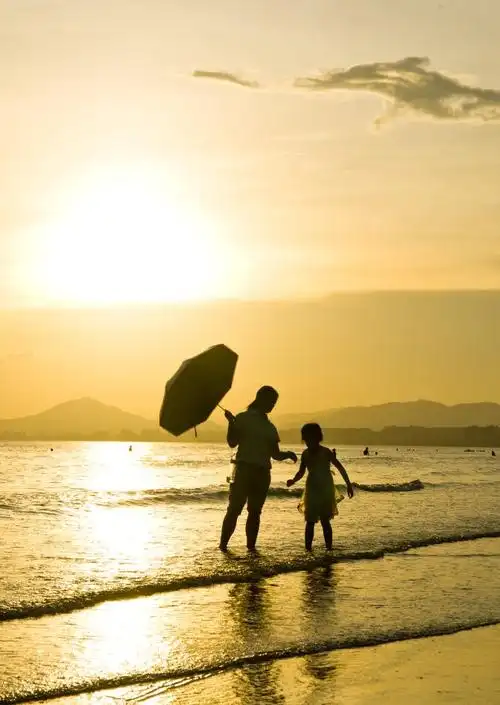 沙滩上一对母女,母亲照看着女儿玩耍